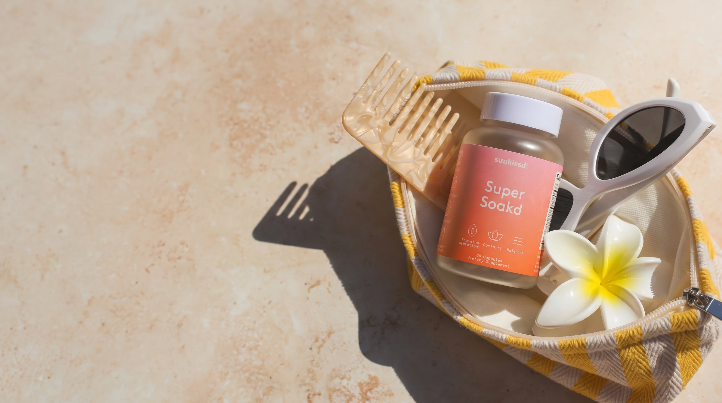 Supplement jar on a tray with a flower and sunglasses on a textured surface