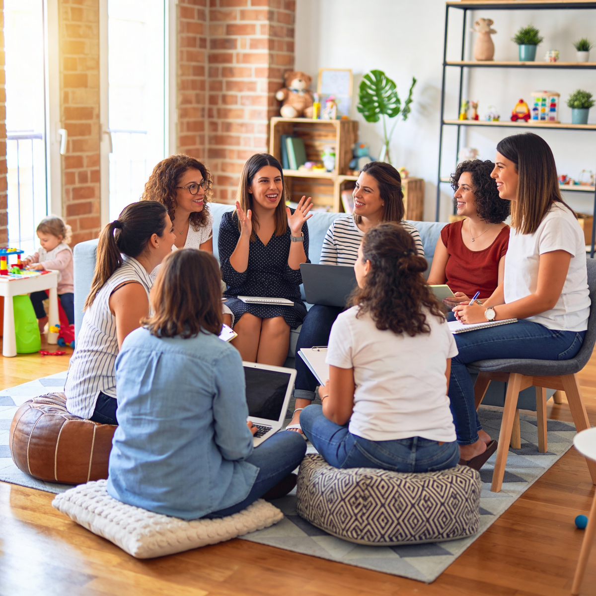 Group of women sitting in a circle in a cozy living room, engaged in a discussion.