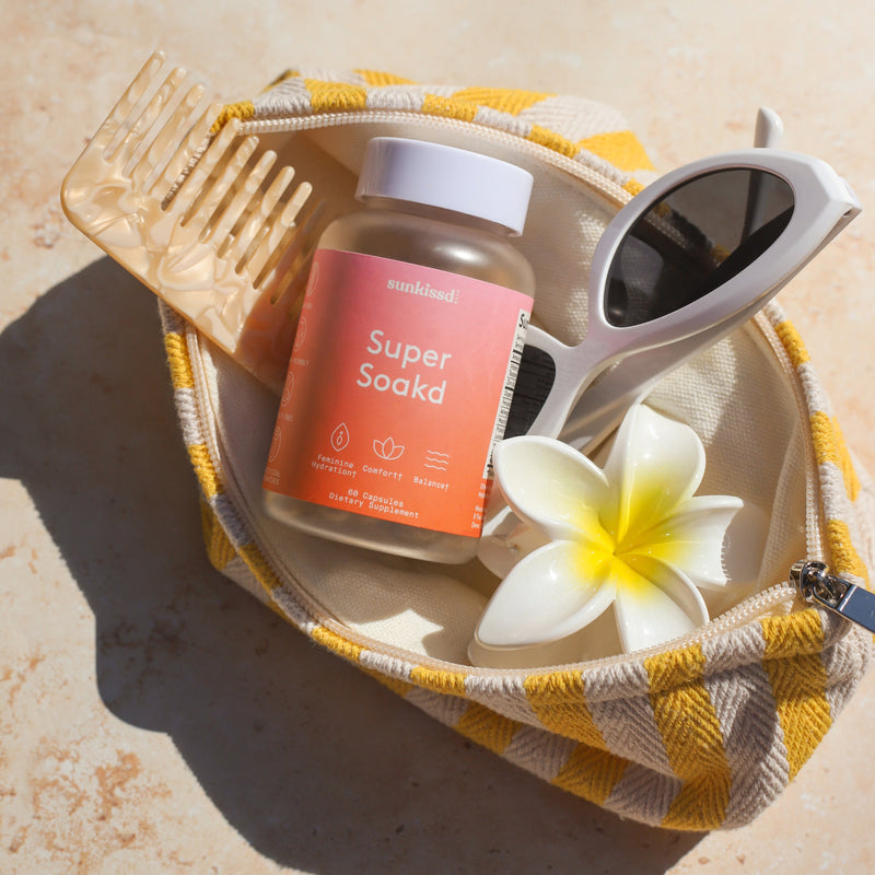 Super Soaked product bottle with a comb, sunglasses, and a flower on a textured surface