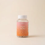A bottle of munsundl Super Soaked dietary supplement capsules, featuring a pink-to-orange gradient label and a white cap, set against a solid beige background.